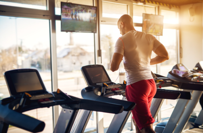 man running in gym with tv in background