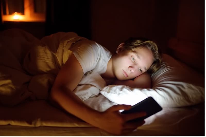 A person lying in bed with a phone